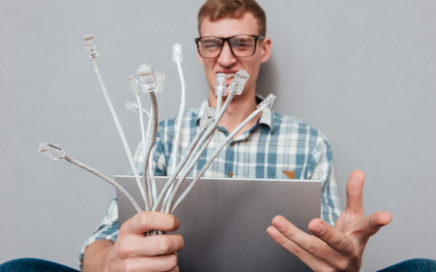 Young student in glasses with laptop and cables. front view