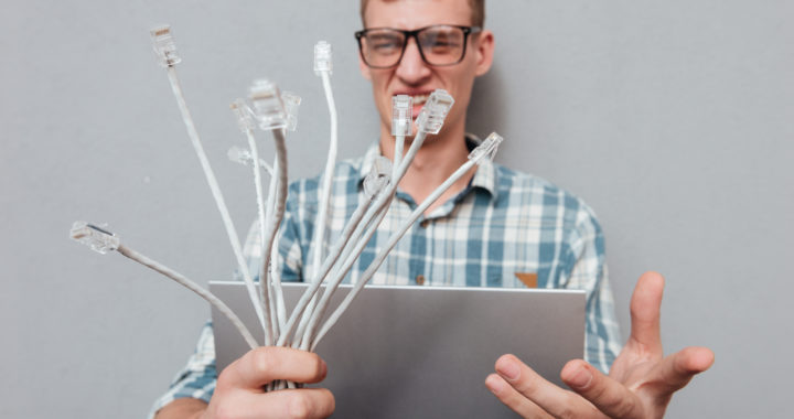 Young student in glasses with laptop and cables. front view