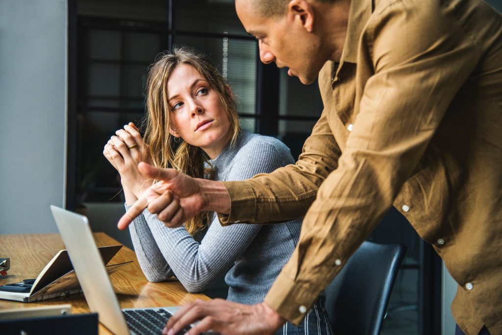 man and woman talking about computer