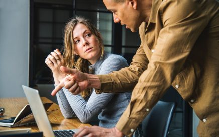 man and woman talking about computer