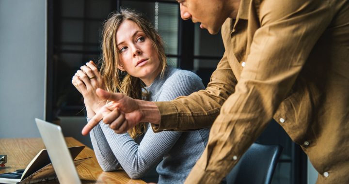 man and woman talking about computer